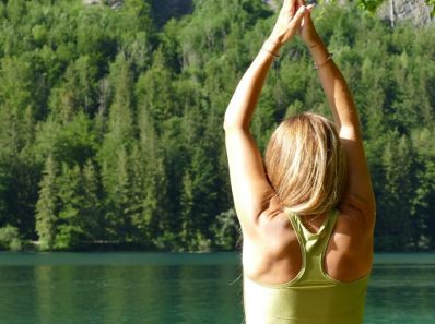 Back view of a woman meditating in a yoga pose by a serene lake in Ebensee, Austria.